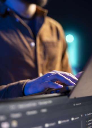 Teleworking programmer doing software debugging using laptop, checking flaws in lines of code displayed on PC monitors. IT admin in apartment fixing coding issues using notebook, close up